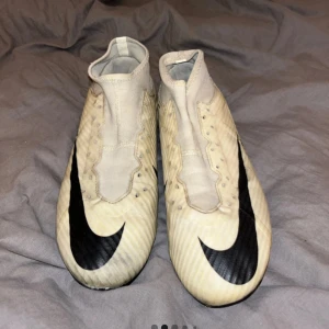 Nike Air Zoom vita/beige fotbollsskor - Säljer ett par vita Nike Air Zoom fotbollsskor med svart swoosh och textdetaljer på sidan. Sitter bra, utan skosnören lite repor osv på dem använda några matcher annars as bra skick .