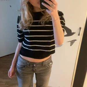 Stickad T-Shirt - Säljer en svart och vit randig stickad T shirt. Perfekt för en avslappnad stil. Toppen har en bekväm passform och är lätt att matcha med jeans eller kjol.