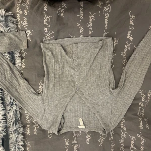 Grå ribbad långärmad bolerotopp - Grå ribbad bolerotopp med lång ärm och knappar framtill. Toppen är croppad. I storlek Xs. Men passar nog även S oxå 