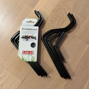 Blomlåds­konsol - 2 st - NYBY blomlåds­konsoler för montering av blomlådor på balkongräcken. Innehåller skruv och mutter. Svart färg, robust metall. Dessa är helt oanvända men den ena saknar tyvärr förpackningen, men innehåller allt den ska (även skruv och mutter.