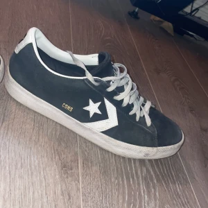 Svarta Converse CONS sneakers i mocka - Säljer ett par svarta Converse CONS sneakers i mocka med vita detaljer och snörning. Skorna har den klassiska stjärnloggan på sidan och Converse-märke bak på hälen. Snygg och tidlös modell med platt sula och rund tå.