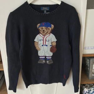 Mörkblå stickad tröja Polo ralph lauren/polobear - Mörkblå stickad tröja från Polo Ralph Lauren med ikoniska Polo Bear stickat framtill. Rund halsringning, ribbade muddar och lång ärm. Perfekt statement-piece för dig som gillar klassisk preppy stil, köpt på kidsbrandstore för några år sedan, fortfarande väldigt bra skick, 8/10. Barnstorlek.