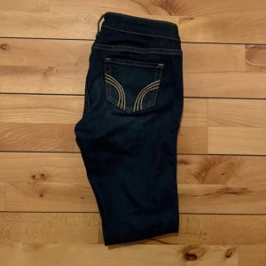 Mörkblå jeans från Hollister - Snygga mörkblå  jeans från Hollister med klassiska kontrastsömmar och femficksdesign. Jeansen har låg midja och är tillverkade i stretchig bomullsblandning för en tight passform. Perfekta för dig som gillar en smal siluett och stilren look.