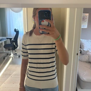 Randig kortärmad tröja från Zara - Säljer en snygg kortärmad tröja från Zara i beige med mörkblå horisontella ränder. Använd men är ändå i bra skick