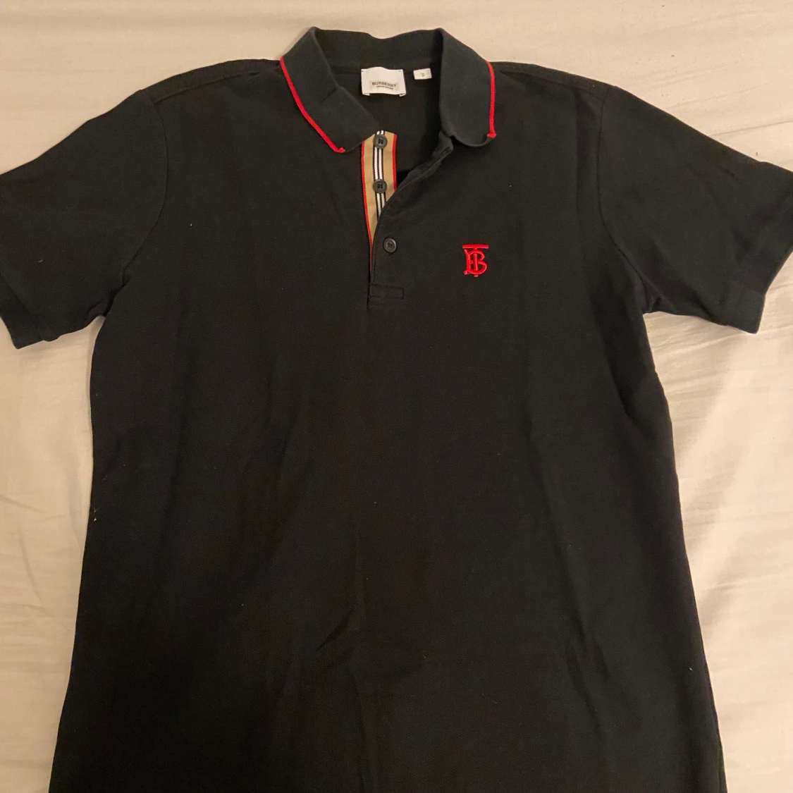 Svart Burberry piké med röd logga