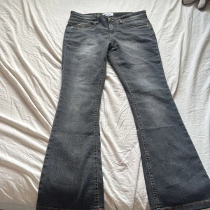 Bootcut jeans från John Baner, grå - Snygga grå bootcut jeans från John Baner i storlek 38. Klassisk femficksmodell med orange kontrastsömmar och broderade bakfickor. Jeansen har en mörk tvätt och är tillverkade i slitstarkt denimtyg. Aldrig använt