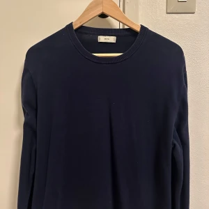 Mörkblå tröja från MNG - En stilren mörkblå tröja från MNG med rund halsringning och långa ärmar. Tröjan har en klassisk passform och är tillverkad i ett mjukt material som passar perfekt till lager-på-lager-stil under höst och vinter. Passar S/M