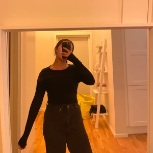 Svart långärmad tröja i slim fit - En svart, långärmad tröja med tight passform och rund halsringning. Tröjan är enkel och stilren, perfekt att matcha med höga jeans eller kjol. Materialet känns mjukt och följsamt mot kroppen.