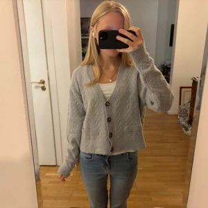 Ljusgrå stickad kofta med knappar - Mysig ljusgrå stickad kofta med v-ringning. 