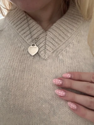 Beige stickad tröja Tiger of Sweden - Mysig beige stickad tröja från Tiger of Sweden med v-ringad hals och bred ribbad kant. Tröjan har lång ärm och en relaxed passform som är perfekt för lager på lager under kyliga dagar. Enkel och stilren design som funkar till allt. Nypris 1999kr. 100% ull