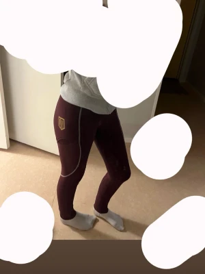 Vinröda ridbyxor från Maya delorez  - STORLEK XXS (passar mig som är 163 lite tajta vid vaden och lår dock) PRIS KAN DISKUTERAS VID SNABB AFFÄR!  Säljer ett par vinröda ridbyxor från Maya delorez med guld logga på låret och helskoning. De har kontrastsömmar i vitt och ett litet hål vid vaden som lätt går att sy igen (syns mer eftersom att dem är lite små i vaden på mig)  Materialet är stretchigt.