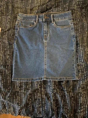 Blå jeanskjol från Vero Moda - Säljer en klassisk blå jeanskjol från Vero Moda. Kjolen har fyra fickor. Den är snygg och fantastisk med ett par strumpbyxor!❤️