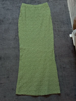 Grön långkjol med struktur - Säljer en långkjol i ljusgrönt med snyggt rynkad struktur. Kjolen har rak passform och resår i midjan för extra komfort. 