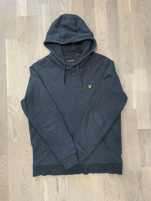Lyle & Scott hoodie- mörkgrå färg  - Stilren och tidlös Lyle & Scott hoodie i mörkgrå färg med den klassiska gula örnloggan på bröstet. Ett populärt och lättmatchat plagg som funkar perfekt både till vardags och för en avslappnad streetwear-look.  • Märke: Lyle & Scott • Typ: Hoodie • Färg: Mörkgrå • Passform: Regular fit • Skick: Mycket bra skick • Klassisk logga på bröstet • Mjuk, bekväm och varm kvalitet  Ett säkert kort i garderoben – enkel, stilren och alltid rätt. Missa inte! Hör av dig vid intresse!