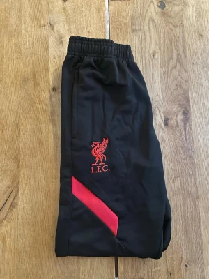 liverpool träningsbyxor - säljer dessa träningsbyxor med laget liverpool. Träningströja finns i min profil. Passar Xs-s. nytt skick 