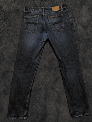 Mörkblå Nudie Jeans - Ett par riktigt snyggt slitna nudie jeans i modellen grim tim(tror jag). Kom gärna med frågor eller prisförslag!