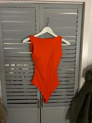 Orange body från Missguided XXS - Säljer en snygg orange body från Missguided i storlek XXS. Bodyn har breda axelband, hög urringning och knäppning i grenen. Perfekt att styla med jeans eller kjol för en cool look.