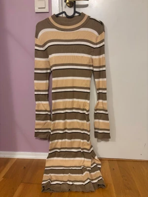 Randig ribbad långklänning Gina Tricot - Säljer en långärmad ribbad långklänning från Gina Tricot i beige, brunt och vitt. Klänningen har ett randigt mönster, rund halsringning och är figurnära i modellen. Perfekt för dig som gillar en enkel men snygg look.