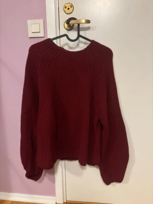 Vinröd stickad tröja LCW Casual - Mysig vinröd stickad tröja från LCW Casual med bred ribbstickning och rund hals. Tröjan har en relaxed passform och långa ärmar, perfekt för kyliga dagar. Snygg att styla med jeans eller kjol för en chill look.