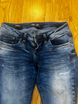 Blå bootcut jeans från LTB - Säljer ett par blå jeans från LTB, modell Valerie. Jeansen har bootcut passform och klassisk femficksdesign. Materialet är jeans med snygga slitningar och tvättade detaljer för en avslappnad look. Perfekta till sneakers eller boots.