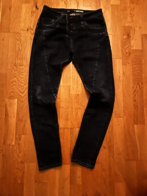 Mörkblå skinny jeans X-Small - Säljer ett par mörkblå skinny jeans i X-Small med hög midja och tre knappar framtill. Jeansen har klassiska fem fickor, kontrastsömmar och bakfickor med unik sömdesign. Perfekta för dig som gillar en tight passform och stilren look.