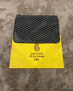 Svart kuvertväska - Säljer en svart kuverväsja med ikoniskt grafiskt mönster i vitt och grått. Väskan har en stilren, rektangulär form och stängs med dragkedja. Perfekt för att bära det viktigaste och ger en lyxig touch till din outfit.