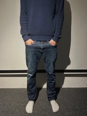 Levis 502 blå jeans - Klassiska blå Levis 502 jeans med rak passform och normal midja. Jeansen har fem fickor, knappgylf och den ikoniska röda Levis-lappen bak. Materialet är slitstarkt denim i bomull och färgen är en snygg mellanblå tvätt. Ett litet hål i bakfickan men inget man tänker på