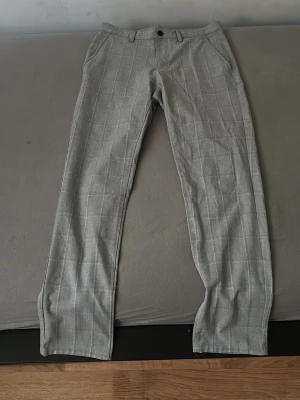 Grå rutiga kostymbyxor från Zara - Säljer ett par stilrena grå kostymbyxor från Zara med diskret rutmönster. Byxorna har raka ben, bälteshällor och fickor både fram och bak. Perfekta för dig som vill ha en clean och klassisk look. Helt nya dem var för små för mig.