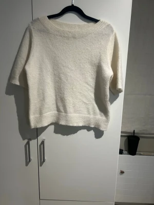 Vit stickad tröja med kort ärm - Mysig vit stickad tröja med korta ärmar och bred ribbad kant vid halsen och nederkanten. Jätte snygg i storlek 158/164💗