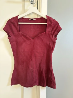 Ribbad vinröd topp från Anna Field - Snygg vinröd ribbad topp med korta ärmar. Toppen har en figurnära passform och är tillverkad i ett mjukt, stretchigt material som känns bekvämt mot huden. 
