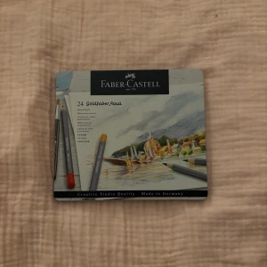 Faber-Castell akvarellpennor 24-pack - Säljer ett set med 24 stycken Faber-Castell Goldfaber Aqua akvarellpennor i metallask. Pennorna har grå kropp och finns i flera olika färger. Perfekt för dig som gillar att rita och måla med vattenfärger. Asken är smidig att ta med och håller pennorna organiserade. 
