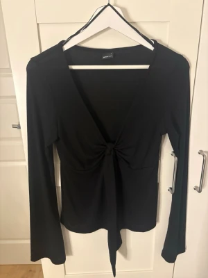 Svart topp  - Snygg svart omlottopp från Gina Tricot med långa ärmar. Toppen har ett knyt framtill som ger en trendig look och är gjord i ett mjukt, stretchigt material. Aldrig använd