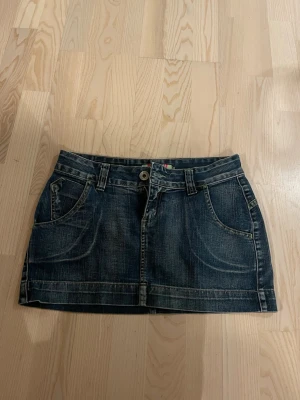 Mörkblå jeanskjol  - Snygg mörkblå jeanskjol med coola backfickor!  Kjolen har en kort passform och slitna detaljer 💗💗💗