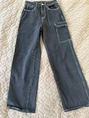 Svarta cargobyxor från SHEIN XS - Snygga svarta cargobyxor från SHEIN i storlek XS. Byxorna har raka ben, kontrastsömmar och en stor ficka på ena benet. Perfekta för en avslappnad streetstil. Materialet är bomullsmix som känns bekvämt hela dagen.