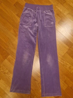 Lila mjukisbyxor Juicy Couture - Säljer ett par lila mjukisbyxor från Juicy Couture i mjuk velour. Storlek XS. I fint skick, men tecken på användning finns.