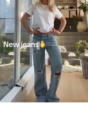 Ljusblåa baggy jeans med hål - Säljer ett par ljusblåa baggy jeans med slitna hål på knäna och raka, vida ben. Jeansen har klassisk femficksdesign och hög midja. Perfekta för en avslappnad och trendig stil.