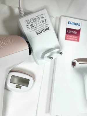 Philips Lumea IPL hårborttagningsapparat - Philips Lumea IPL hårborttagningsapparat i vitt och ljusrosa. Inkluderar laddare, extra huvud, förvaringspåse och manual. Perfekt för smidig och långvarig hårborttagning hemma. Enkel att använda och stilren design.