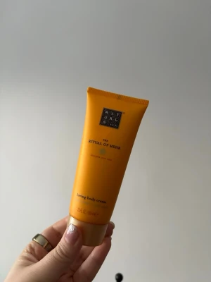 Rituals The Ritual of Mehr bodylotion  - Fräsch och energigivande body cream från Rituals, The Ritual of Mehr. Kommer i en orange tub med svart och guldigt märke. Innehåller 100 ml och har en krämig konsistens som återfuktar huden. Perfekt för dig som vill ha en lyxig känsla i vardagen. Endast testad så nästan full (se bild 2)