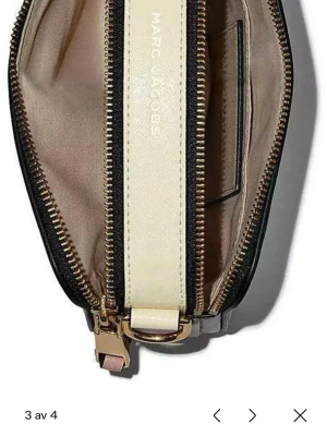 Marc Jacobs Snapshot axelväska, den är använd mycket men inget man ser på utsidan det är mest tyget inne som har lite smink kläckar, säljer den då jag inte använder den längre, köpte för 4400kr för 3 år sen ungefär  - Trendig axelväska från Marc Jacobs i beige och rosa med detaljer i svart och guld. Väskan har en bred, justerbar axelrem med logotyp, dubbla dragkedjor och en ficka på utsidan. Tillverkad i slittåligt läder och textil. Perfekt för dig som vill ha en snygg och praktisk väska.