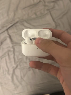 Apple AirPods med laddningsetui - Säljer ett par vita Apple AirPods med trådlöst laddningsetui. Snygg och kompakt design i plast, perfekt för dig som vill ha smidiga hörlurar till mobilen. Passar både till musik och samtal, och laddas enkelt i det medföljande etuiet.