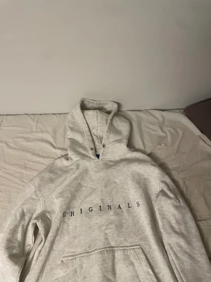 Ljusgrå hoodie från Jack & Jones - Säljer en ljusgrå hoodie från Jack & Jones Originals med svart text på bröstet. Tröjan har huva med metallöljetter, stor magficka och långa ärmar. Perfekt för chill dagar och enkel att matcha med jeans eller joggers. 