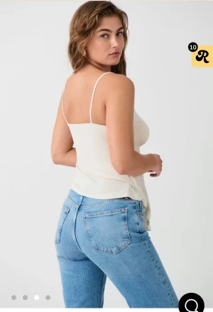 Krämvit linnetopp med knyt framtill - Säljer en krämvit linnetopp med smala axelband och snygg knytning framtill. Toppen har en lätt v-ringning och är tillverkad i ett mjukt, tunt material som faller snyggt. Perfekt för varma dagar och enkel att styla med jeans eller kjol.