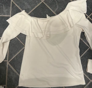 Vit offshoulder volangtop från NLY Trend - Supersöt vit offshoulder topp från NLY Trend i storlek XS. Toppen har långa ärmar och bred volang runt hela axelpartiet, den är använd men fortfarande bra skick!!💕går att diskutera pris!