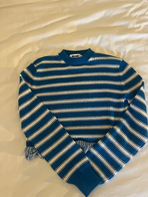 Blåvit randig stickad tröja MSGM - Säljer en blå och vit randig stickad tröja från MSGM med grov struktur och ribbad hals. Tröjan har lång ärm och coola fransar längs nederkanten som ger en unik vibe. Perfekt för dig som gillar statement-plagg och italiensk design. Frakt står köparen för!nypris:2800
