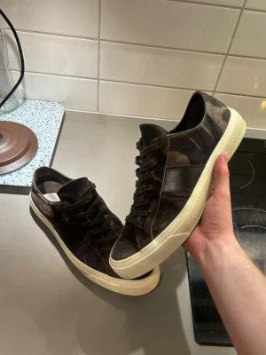 Tom Ford skor - Snygga sneakers från Tom Ford i camo mönster (färgerna), khaki, brun och svart. Skorna är i super skick, pris kan diskuteras. Skriv om ni undrar över något!