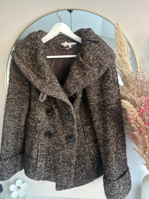 Brun rutig skepparkavaj från Zara Basic - Säljer en brun och beige rutig skepparkavaj från Zara Basic. Jackan har bred krage, dubbelknäppning med stora svarta knappar och är i en ullmix. Sönder vid sömen vilket syns på sista bilden, skadan är inte synlig när jackan är på