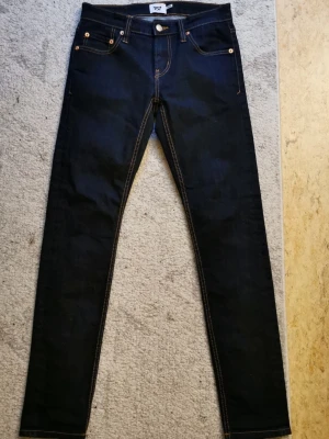 Mörkblå Levi's 511 jeans - Säljer ett par mörkblå Levi's 511 jeans med klassisk femficksdesign och kontrastsömmar. Jeansen har en slim passform och är tillverkade i slitstarkt denimtyg. Perfekta för dig som gillar en tidlös och clean look.