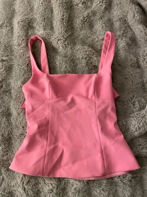 Rosa linnetopp med rosett från Zara - Söt rosa topp från Zara med breda axelband och en stor rosett i ryggen. Använd tre gånger, nopprat något vid bröstet (bild 4), annars superfin. Sorlek M men lite liten i storlek. 