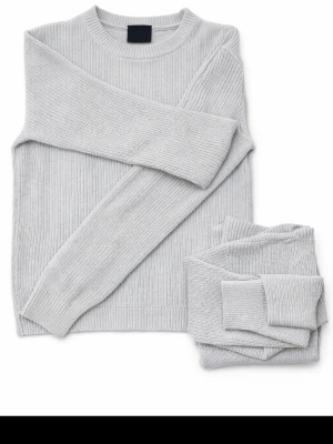 Ljusgrå stickad tröja med rund hals - Snygg ljusgrå stickad tröja med rund hals och ribbade muddar. Tröjan har en klassisk, enkel design med långärmade ärmar och är perfekt för lager-på-lager. Passar dig som gillar stilrena och bekväma plagg.