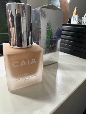 CAIA It's Iconic Liquid Silk Foundation 2N - Säljer en CAIA It's Iconic Liquid Silk Foundation med SPF 20. Kommer i en frostad glasflaska med silvrig kork och originalkartong. Innehåller hyaluronsyra och vitamin C för extra glow. Färgen är ljusbeige och ger en naturlig finish.